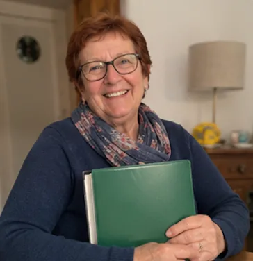 Christine F. serrant son dossier familial dans ses bras