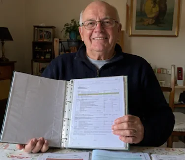 Jean-Pierre B. à sa table avec son dossier rempli